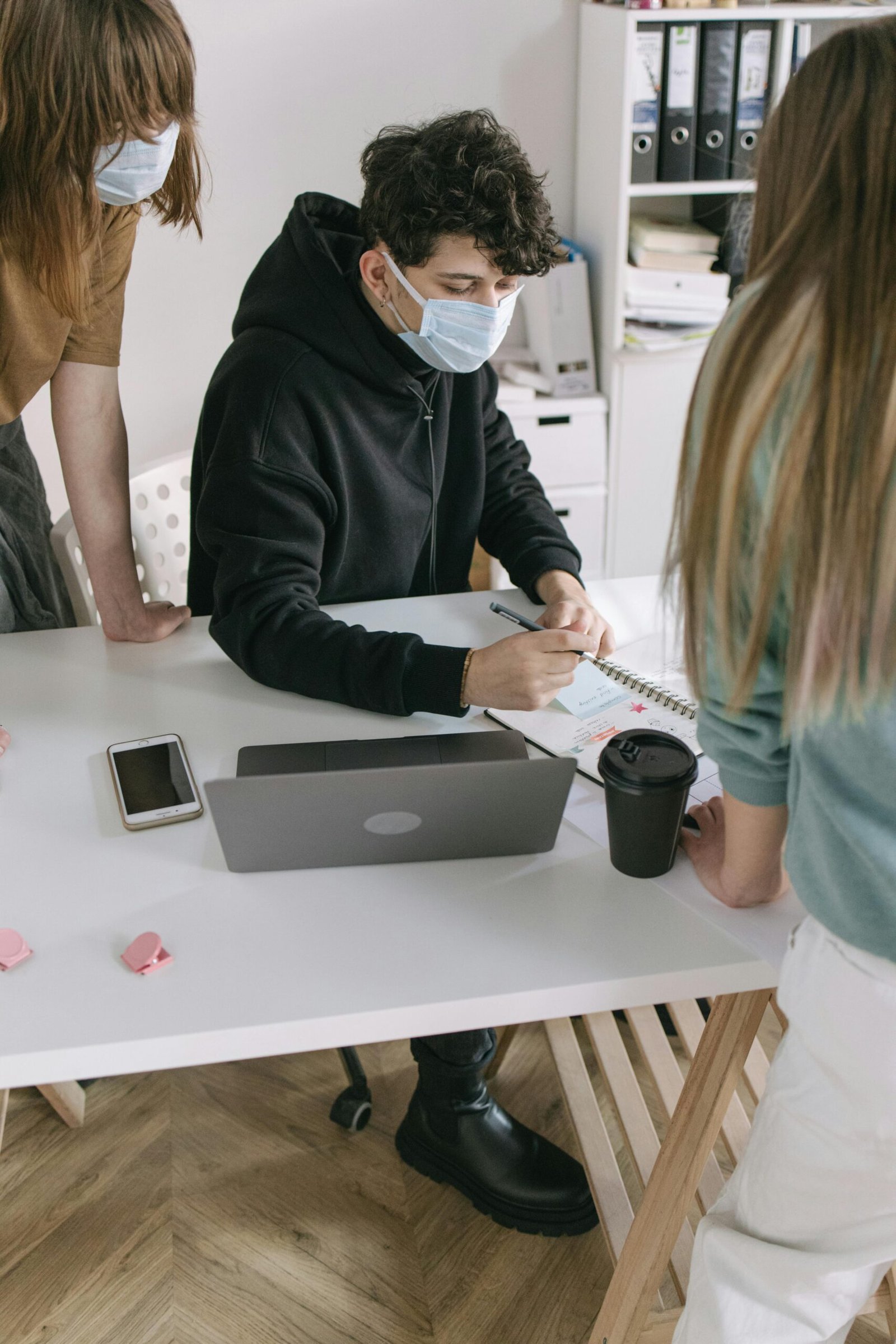 A diverse team collaborating with masks in a modern office setting.